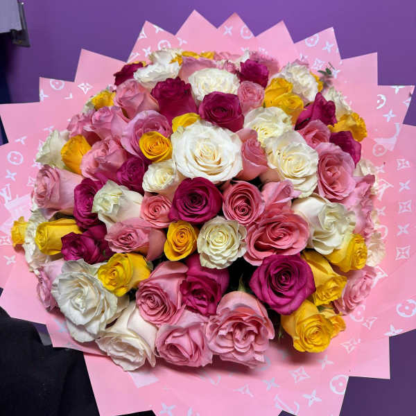 Bouquet of pink, white, and yellow roses wrapped in pink paper