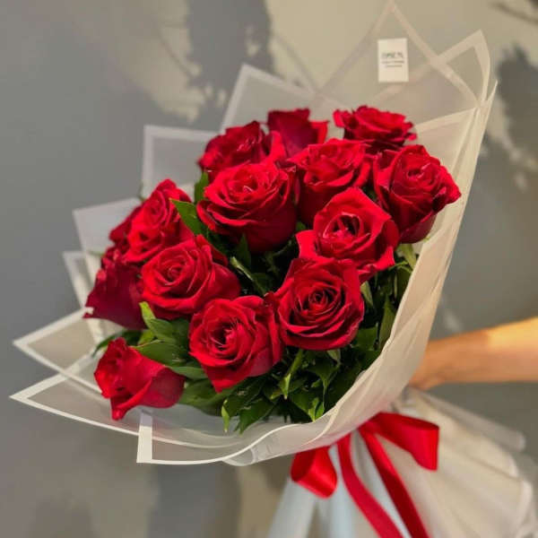Bouquet of red roses wrapped in white paper with a red ribbon