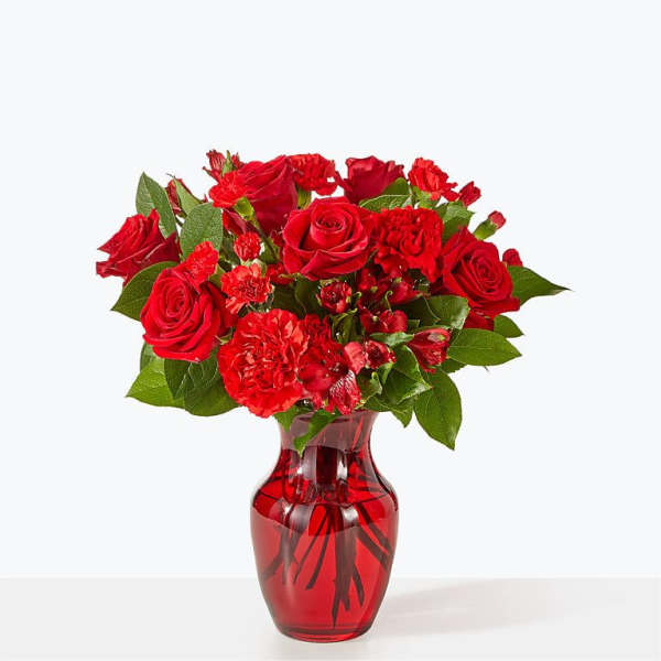 Red roses and carnations in a red glass vase