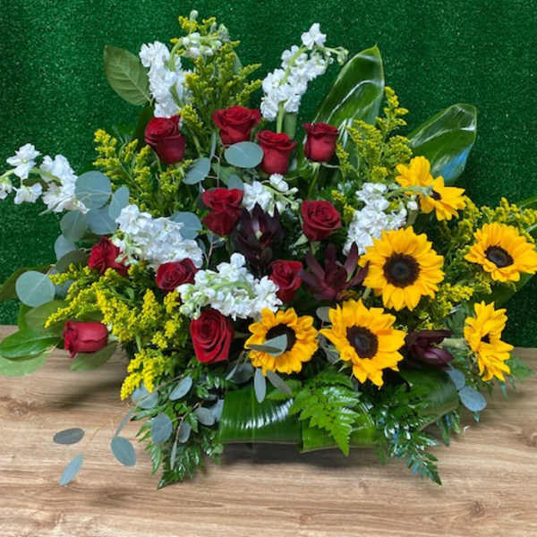 Red roses and yellow sunflowers in a low floral arrangement