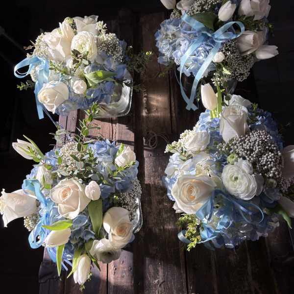 Four blue and white floral bouquets with ribbon on a wooden surface