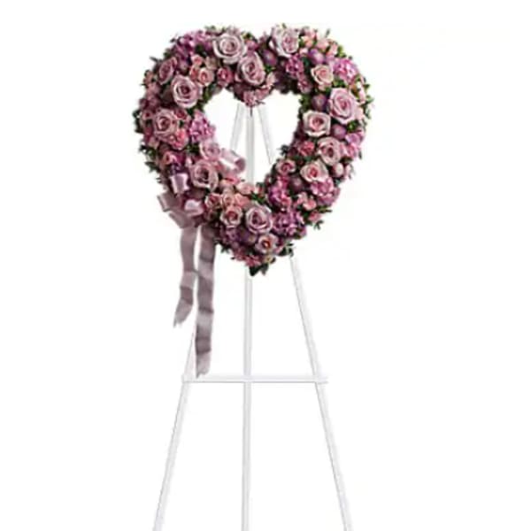 Heart-shaped pink rose wreath on a standing easel with ribbon