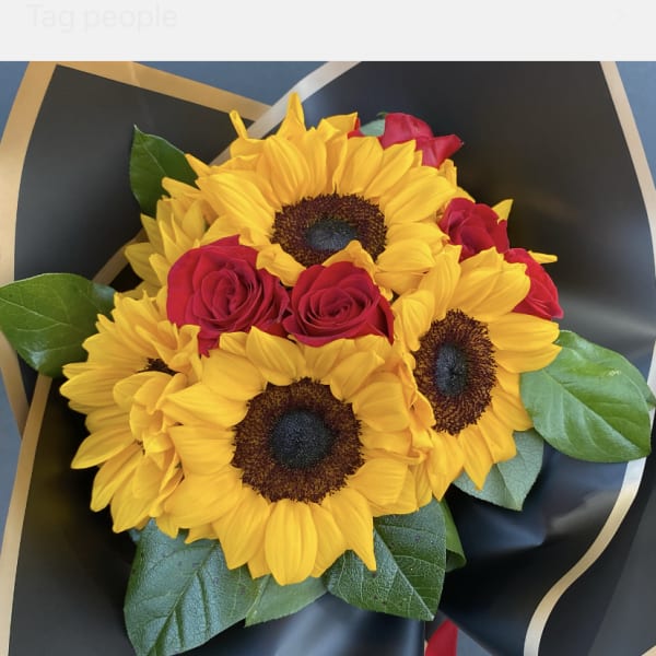 Bouquet of yellow sunflowers and red roses wrapped in black paper