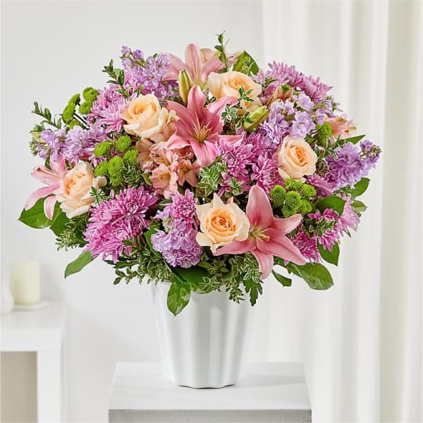 Pink lilies, roses, and purple mums in a white vase