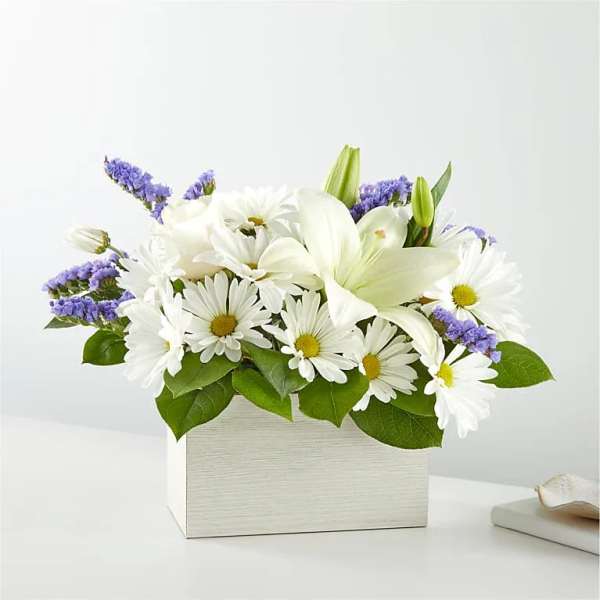 White daisies and lilies in a white box with purple accents