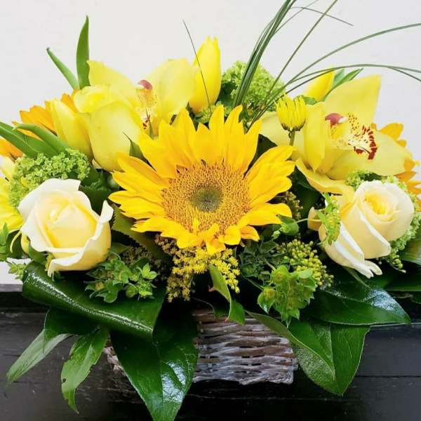 Yellow sunflower and white rose arrangement in a wicker basket