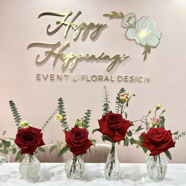 Four red rose arrangements in clear glass vases on a table