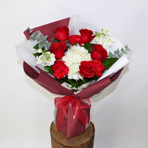 Bouquet of red roses and white flowers wrapped in burgundy paper