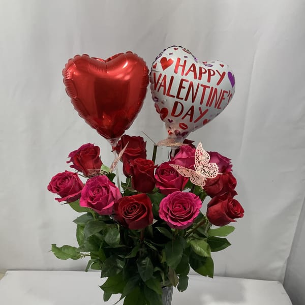 Red and pink roses in a vase with two heart balloons