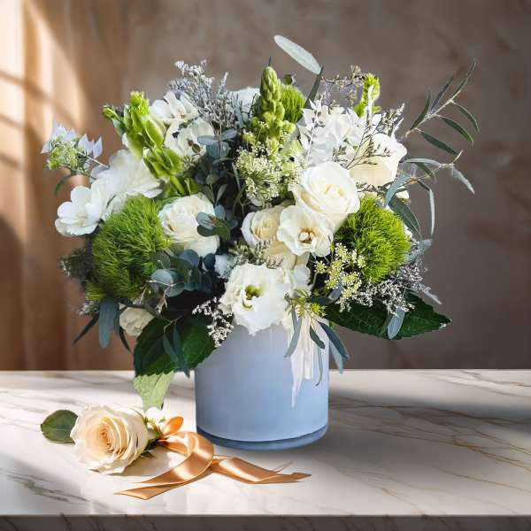 White floral arrangement in a blue vase with a rose on the table