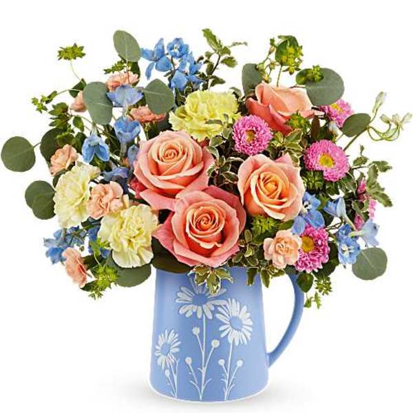 Mixed bouquet of roses, daisies, and blue flowers in a blue pitcher