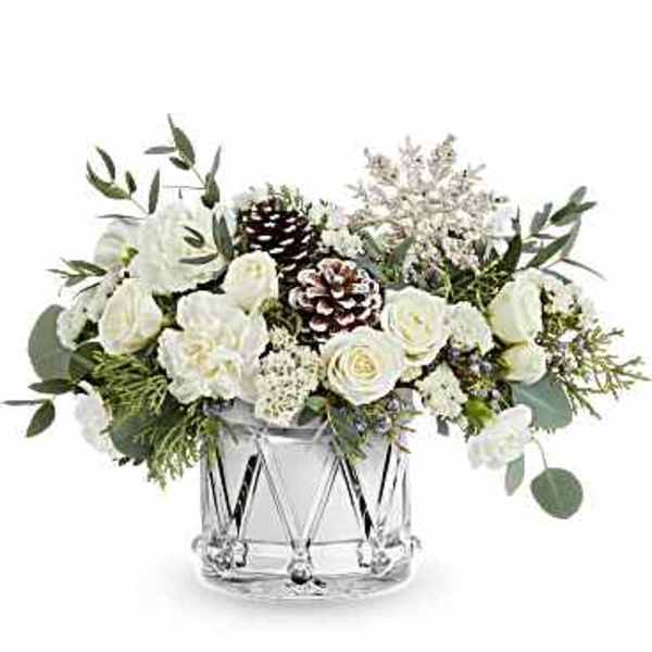 White floral arrangement in a clear glass vase with pinecones