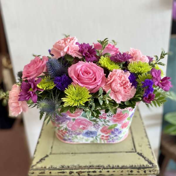 Pink and purple mixed flower arrangement in a floral box