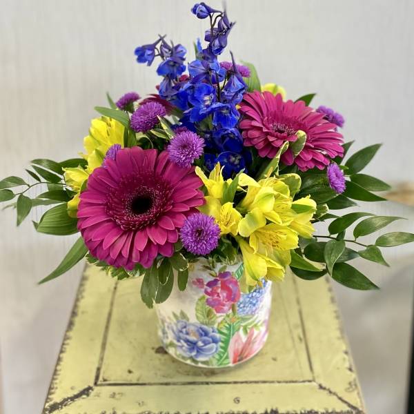 Bright mixed bouquet in a floral tin container
