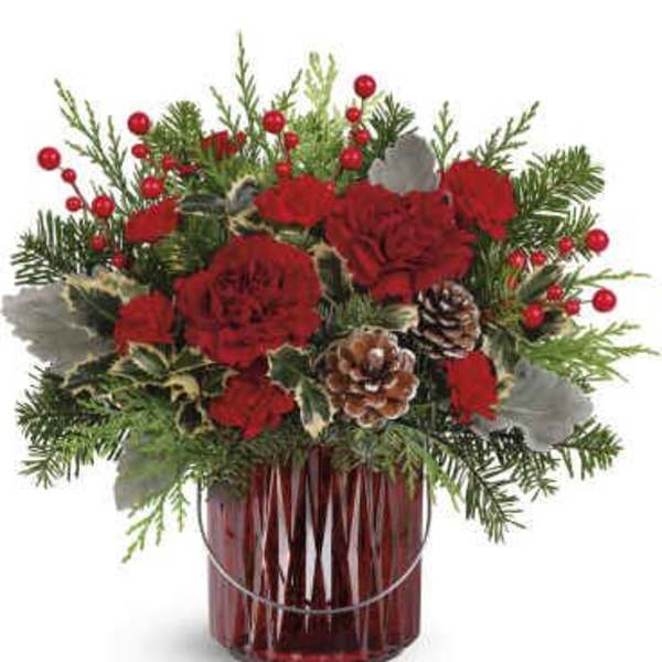 Red carnations in a red glass vase with pinecones and evergreen accents