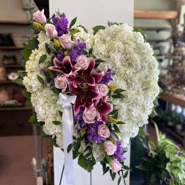 Heart-shaped floral spray with white hydrangeas, pink roses, and purple lilies