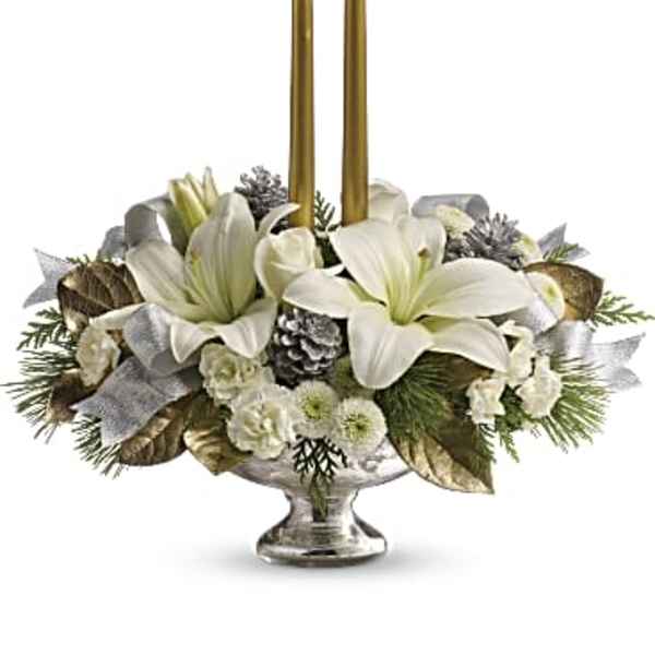 White floral centerpiece with two gold taper candles in a silver bowl