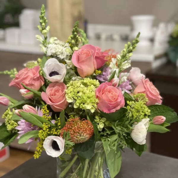 Pink roses and mixed blooms arranged in a clear glass vase
