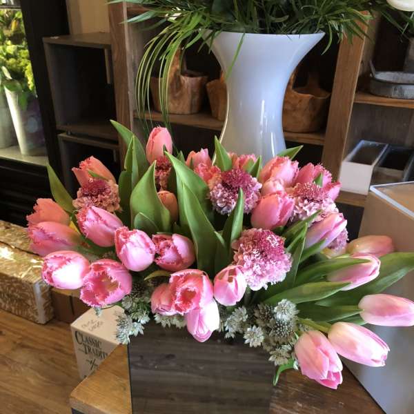 Pink tulips and carnations arranged in a dark square box