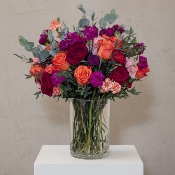 Bouquet of red, orange, and purple flowers in a clear glass vase