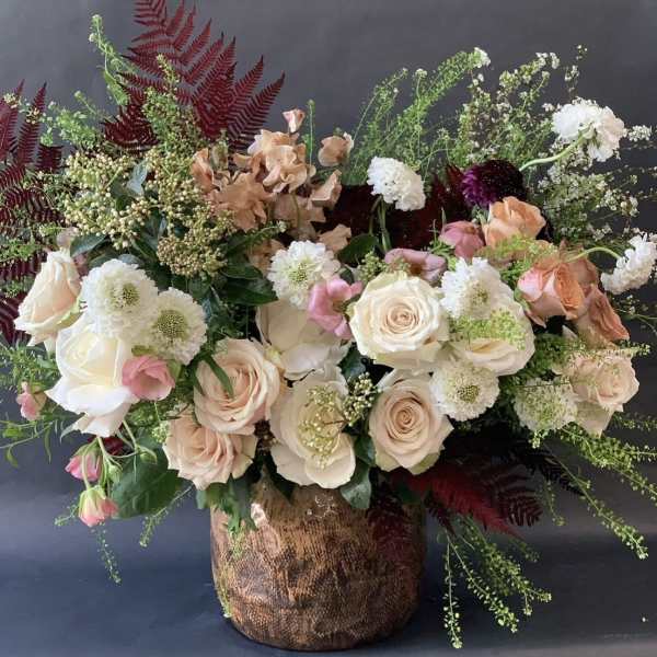 Large bouquet of blush and white roses with mixed blooms in a textured vase