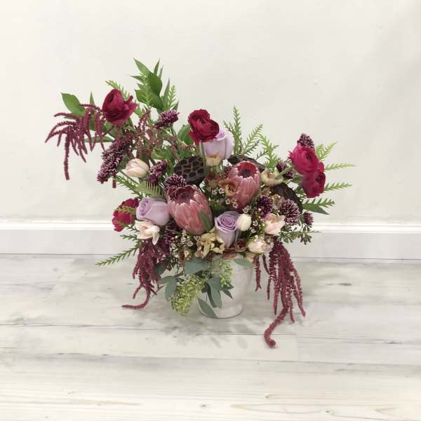 Mixed pink and burgundy floral arrangement in a white vase