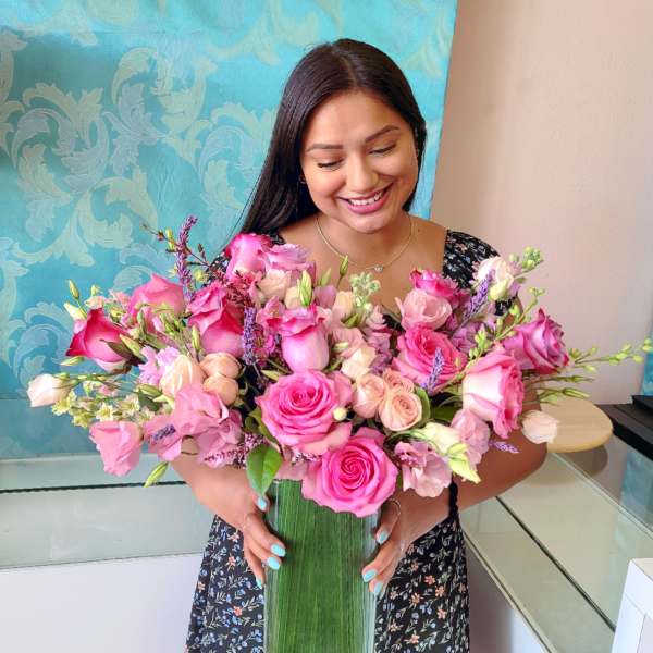 Woman holding a large pink rose bouquet in a tall glass vase