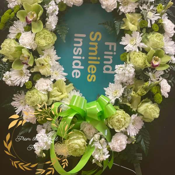Green and white floral wreath with a bright ribbon bow