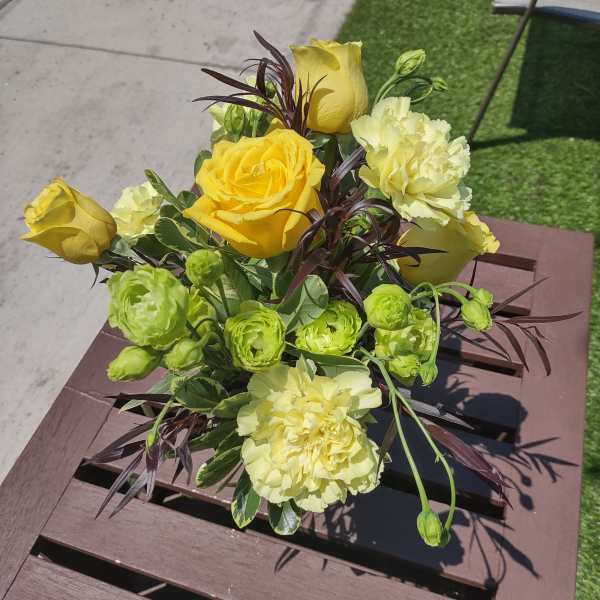 Yellow roses and pale carnations in a compact bouquet
