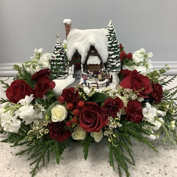 Winter floral arrangement with a snowy cottage centerpiece and red and white roses