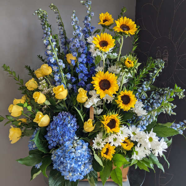 Mixed bouquet with sunflowers, yellow roses, blue hydrangeas, and white daisies