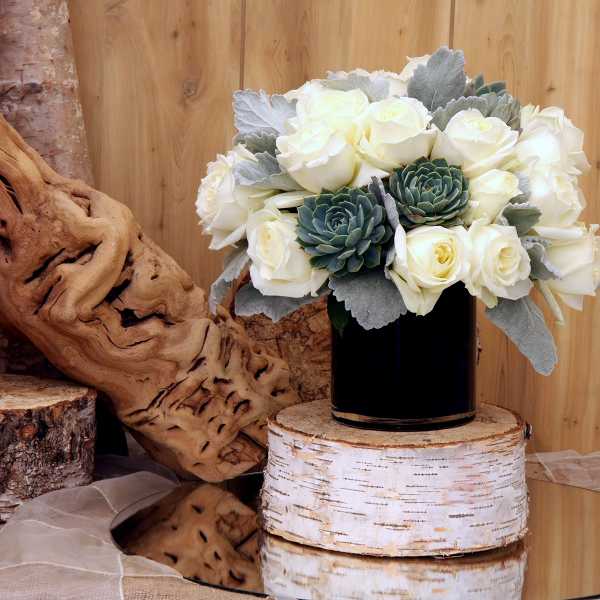 White roses and green succulents in a black vase