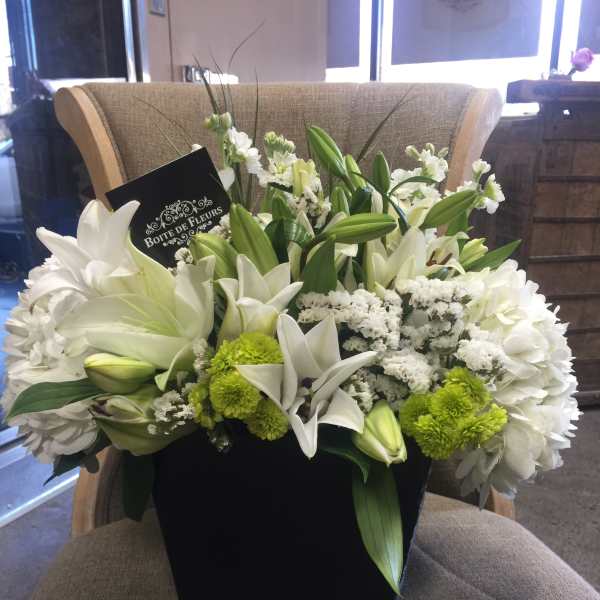 White lilies and green chrysanthemums in a black box arrangement
