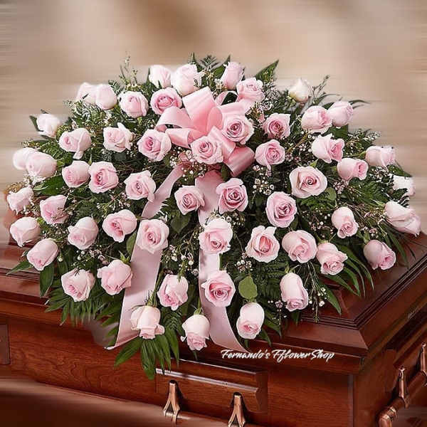 Pink rose casket spray with ribbon on a wooden casket