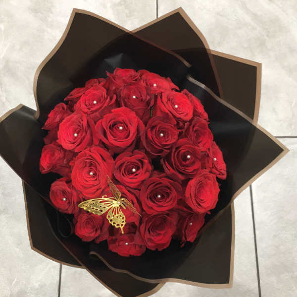 Bouquet of red roses wrapped in black paper with a gold butterfly accent