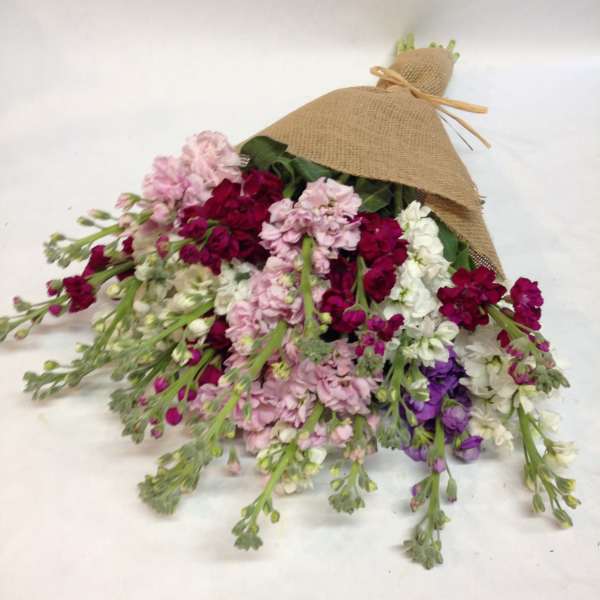 Bouquet of pink, white, and purple flowers wrapped in burlap