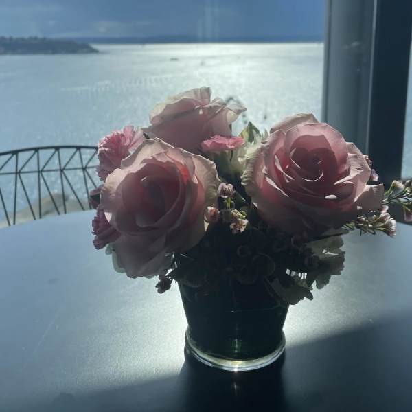 Pink rose bouquet in a small glass vase on a table by a window