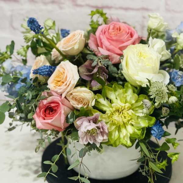 Mixed bouquet of pink, white, and blue flowers in a white vase