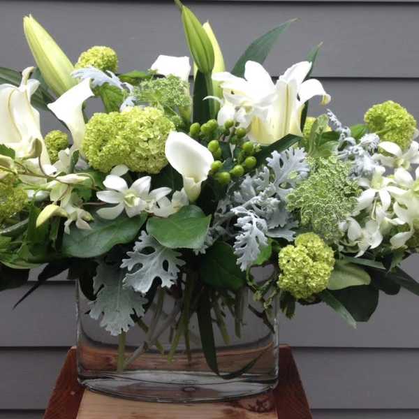 White lilies and green blooms in a clear glass vase