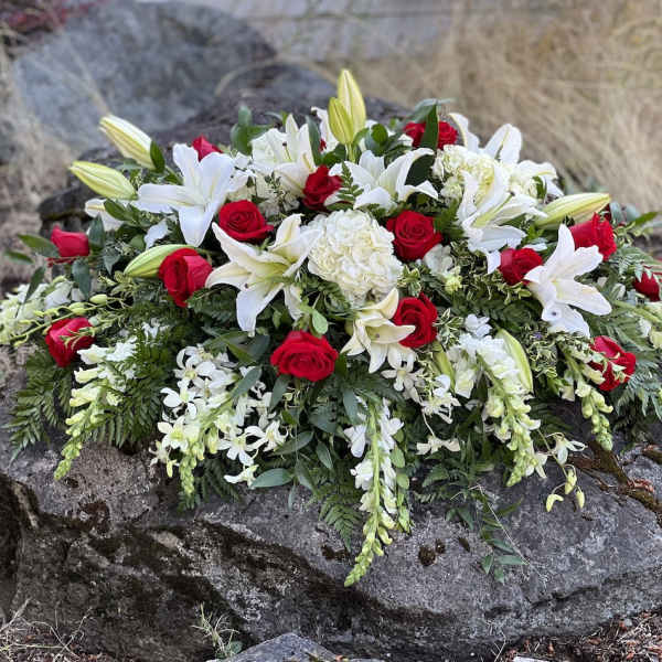 Casket spray of red roses and white lilies with trailing white flowers