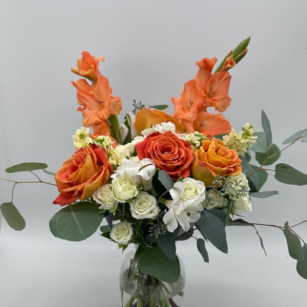 Orange roses and white flowers in a clear glass vase