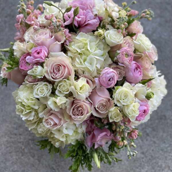Round bouquet of pink and white roses with pale hydrangeas