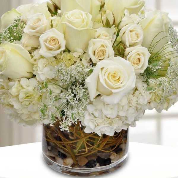 White roses and hydrangeas arranged in a glass vase.