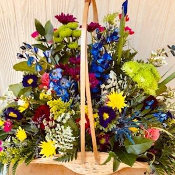 Large basket arrangement of multicolored flowers with a wooden handle