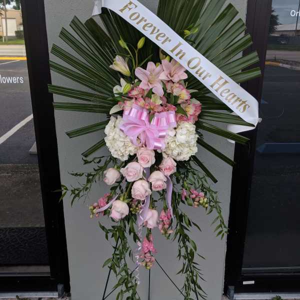Standing floral spray with pink and white flowers and a memorial ribbon