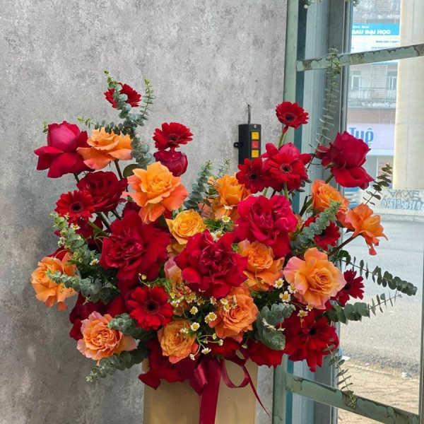 Large bouquet of red and orange roses and gerbera daisies in a box