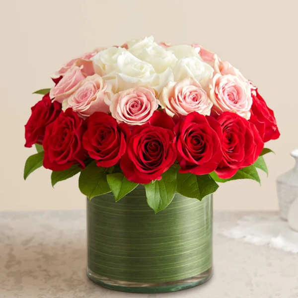 Red and blush roses arranged in a green glass vase