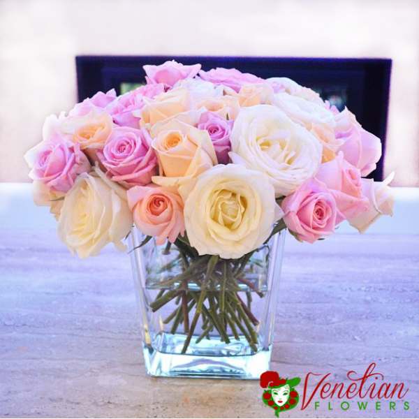 Pink and white roses arranged in a clear glass vase