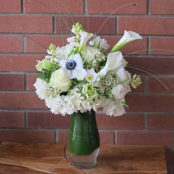 White floral arrangement in a green glass vase