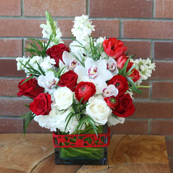 Red and white floral arrangement in a square glass vase